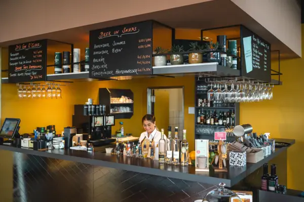 A woman behind a bar with bottles in the background