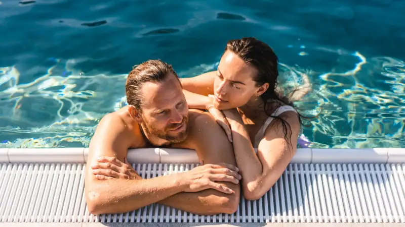 Outdoorpool A man and woman in swimwear enjoying a swimming pool.