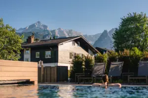 Eine Person im Außenpool vor einem Haus.