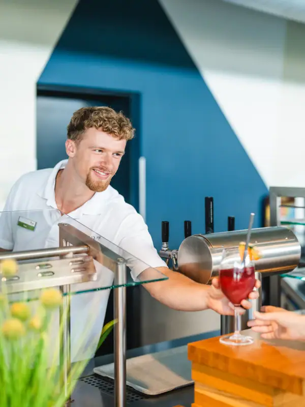 A man hands a customer a drink.