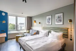 Rooms at the aja Warnemünde A room with a double bed, pictures on the wall and a sofa.