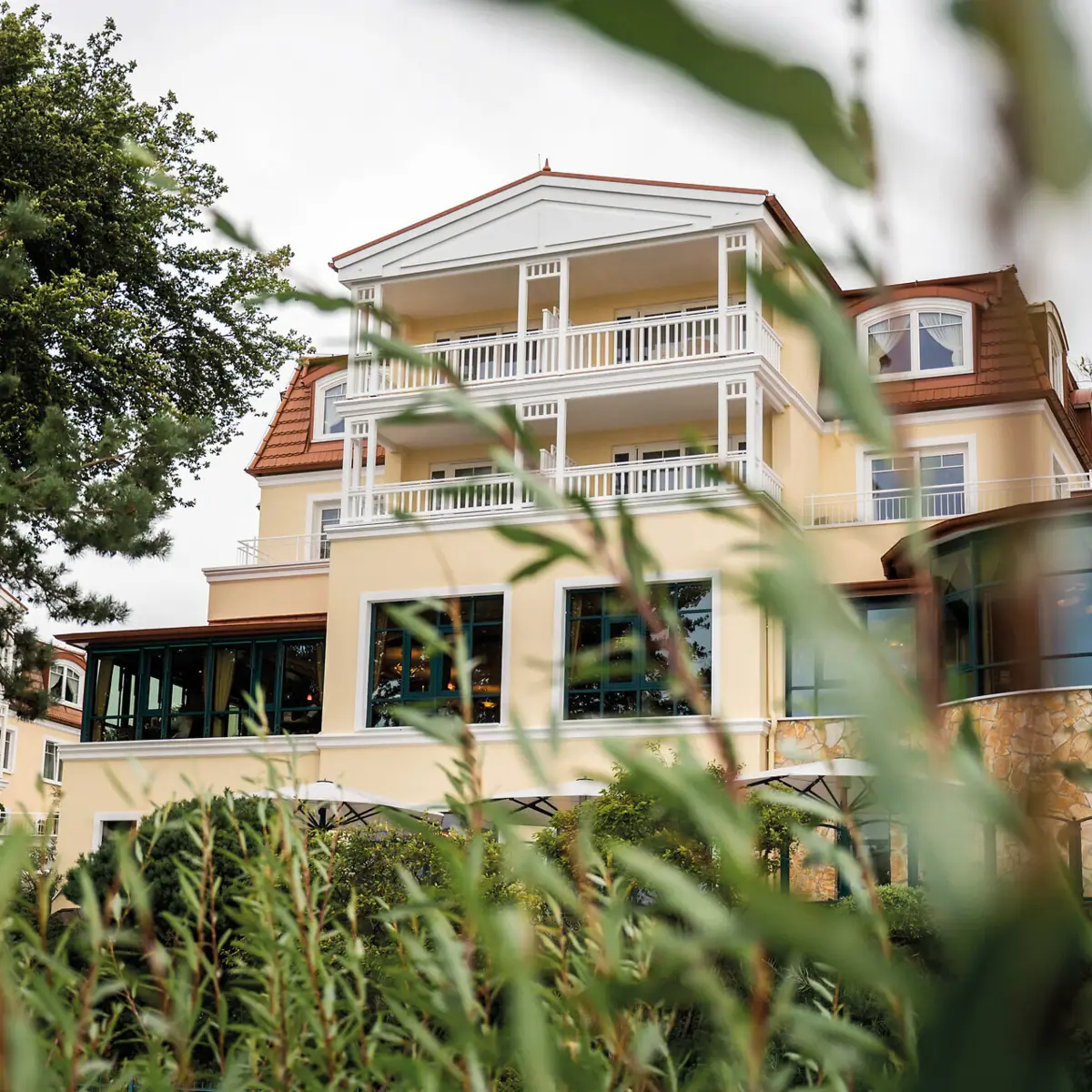 aja Hotel Usedom A building with windows and trees in the background.