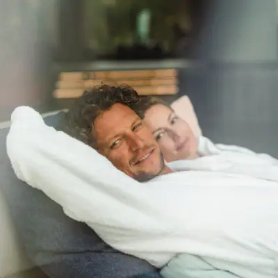 A man and a woman are lying comfortably on a sofa.