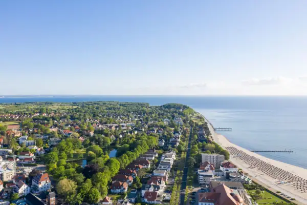 Travemünde coast Aerial view of a town on the water with buildings and trees in the foreground.
