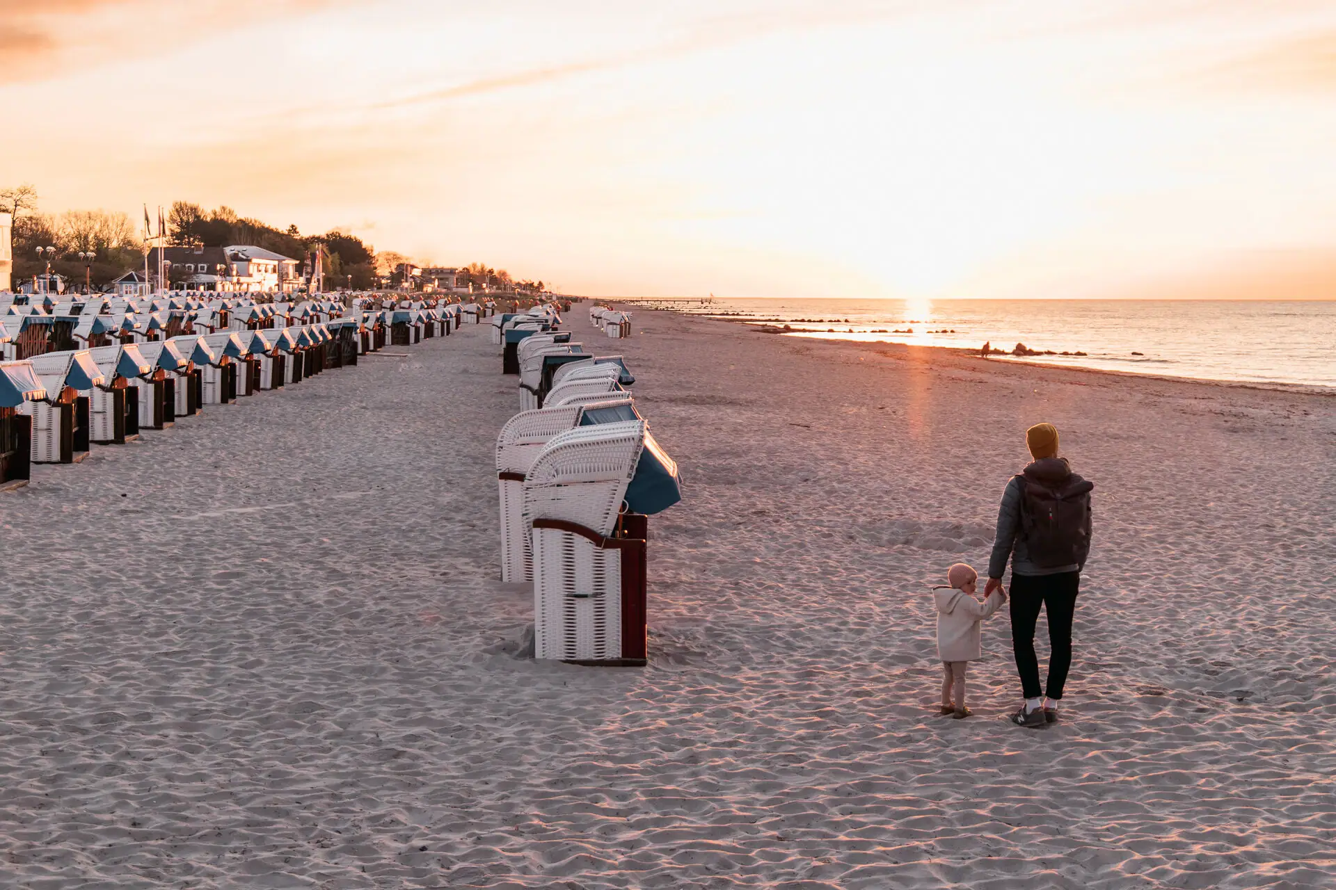 A man and a child walk along the beach.