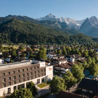 aja Garmisch City with trees in the foreground and mountains in the background.