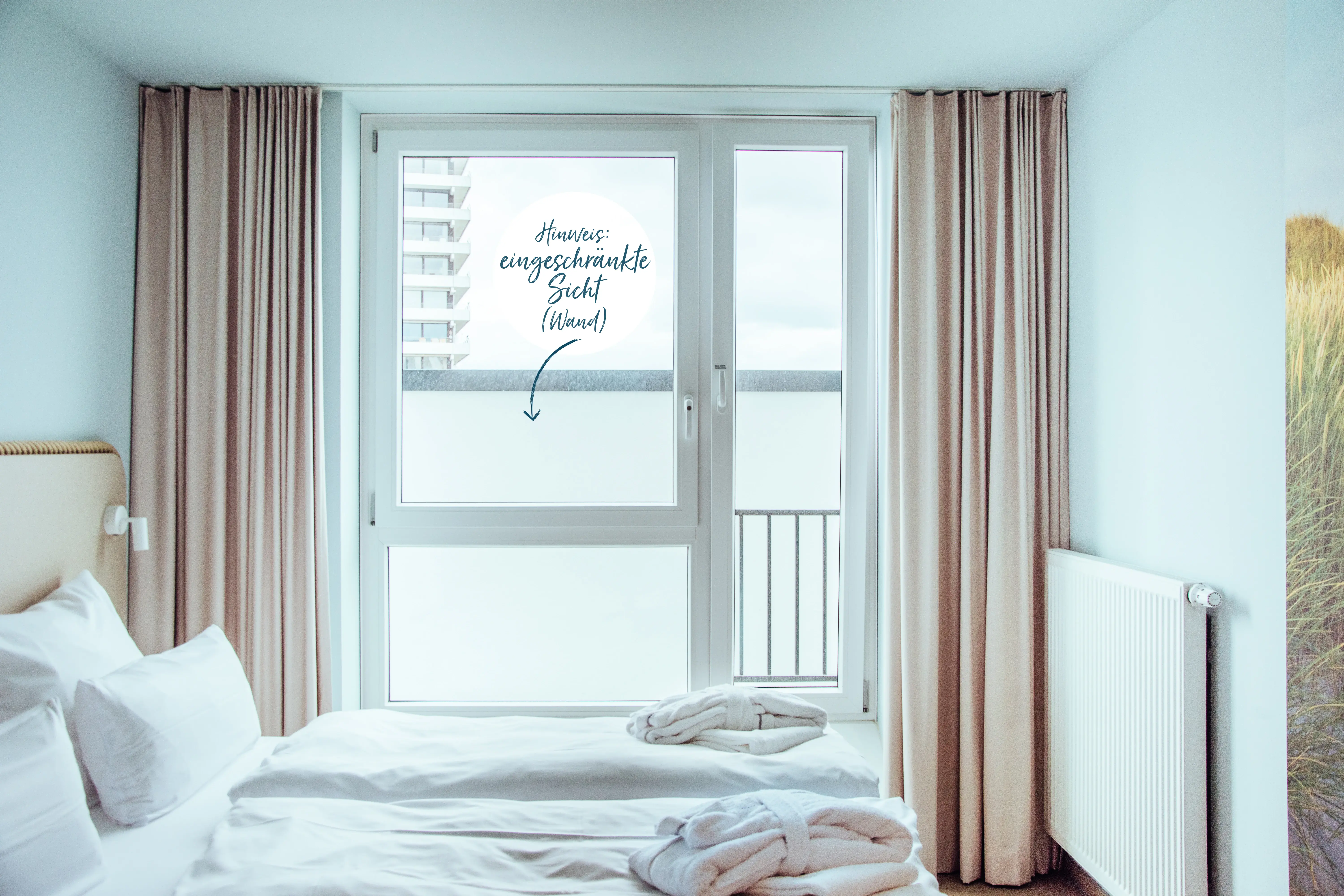 A bright hotel room showcasing a neatly made bed and a large window with limited visibility due to a wall, highlighted with a note.