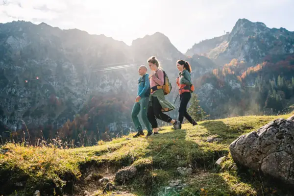 Hiking in the Chiemgau A group of people hiking on a hill with mountains in the background.