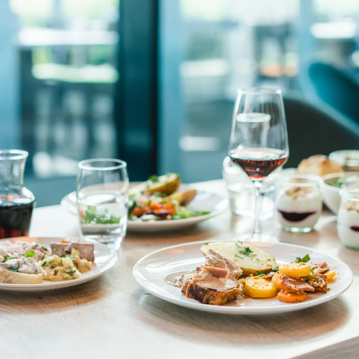 A table with plates full of food and glasses of wine.