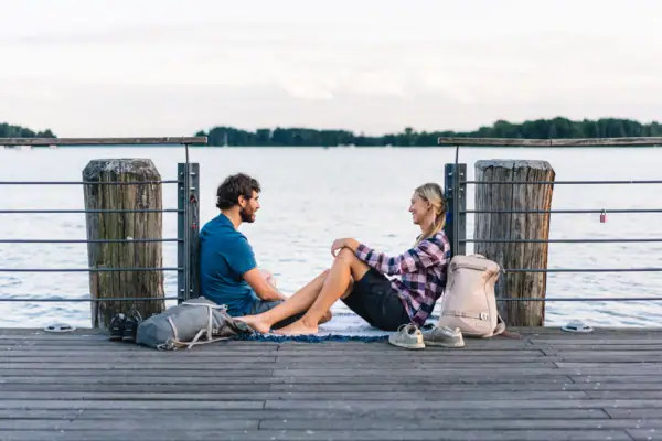 Scharmützelsee A man and a woman are sitting on a jetty with water in the background.