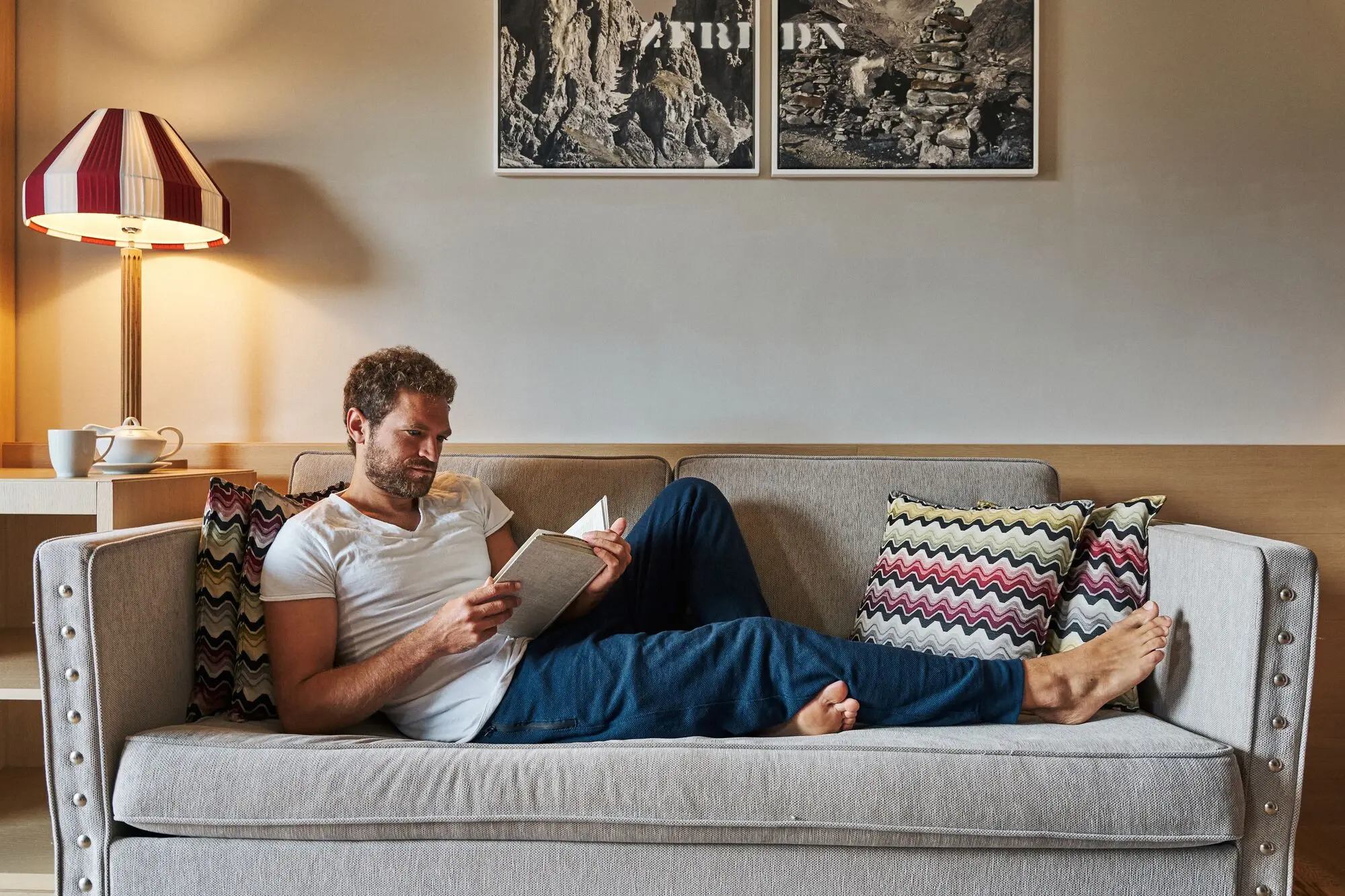 A man reads a book on a sofa.