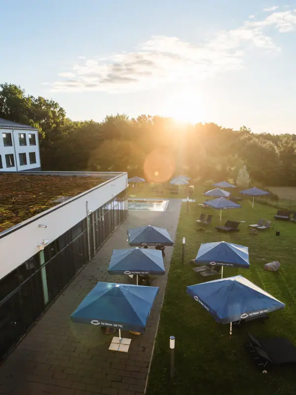 aja Bad Saarow A building with parasols and chairs on a lawn.