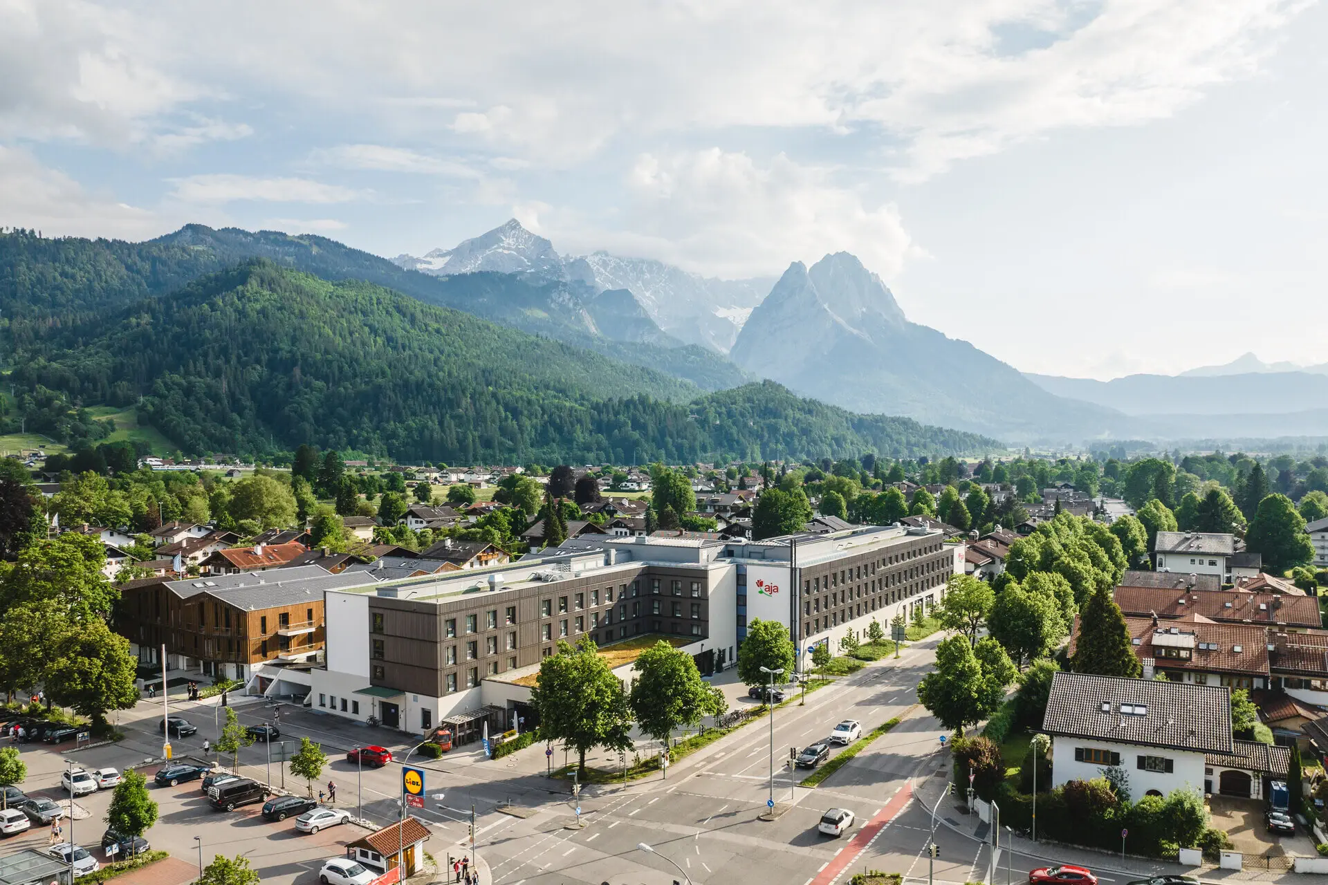 Cityscape with numerous buildings and trees against a mountain backdrop