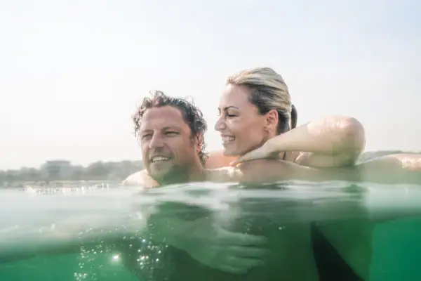 Warnemünde Meer Ein Mann und eine Frau im Wasser, beide lächelnd.