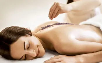 A woman is lying on her stomach and has a purple peeling on her back.