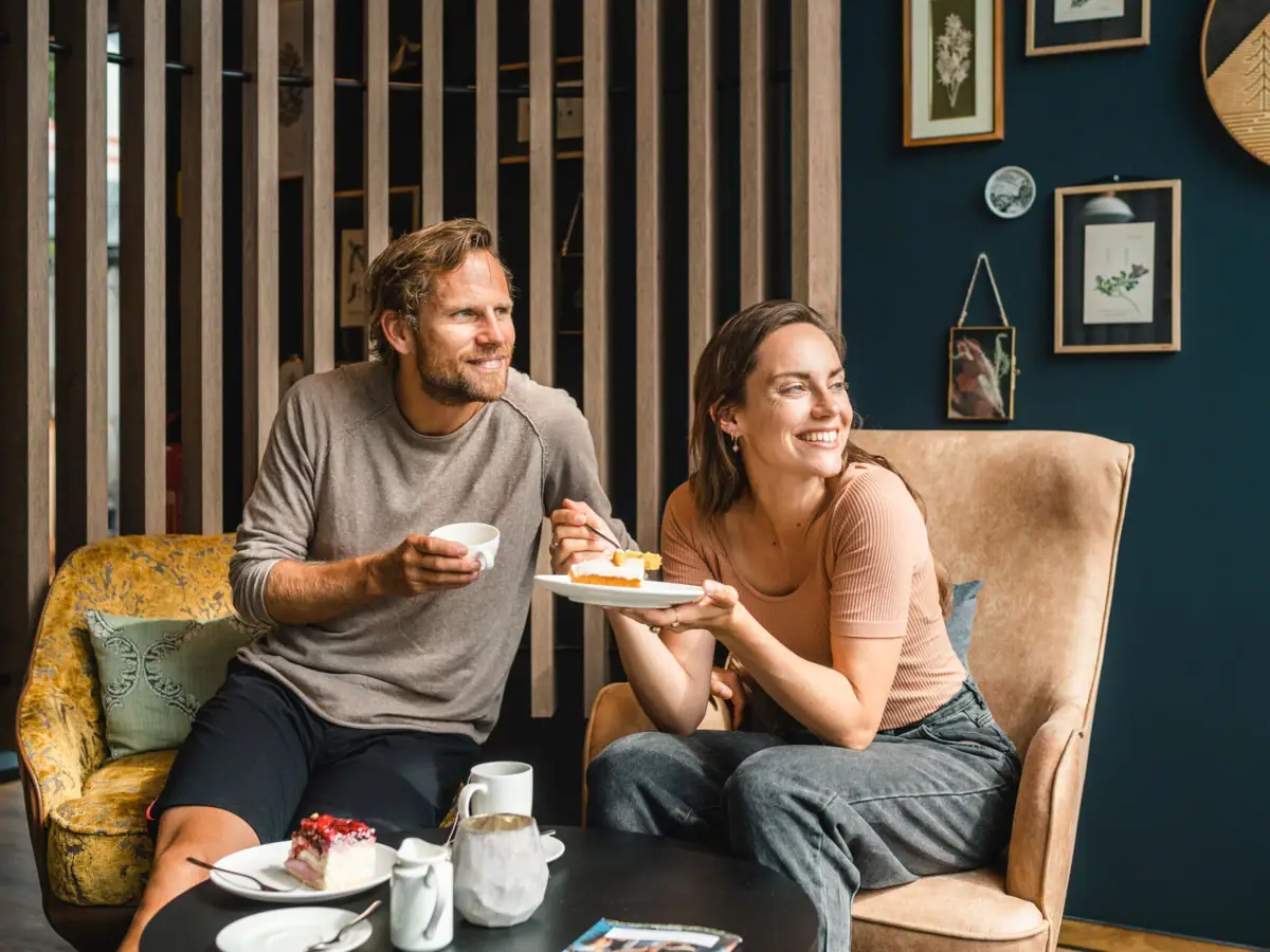 Coffee break A man and a woman are sitting on a chair eating cake.