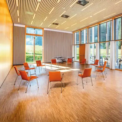 A room with chairs and tables, featuring interior design elements and large windows.