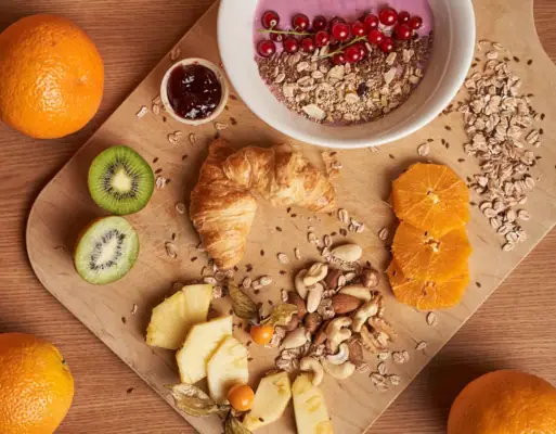 Breakfast A plate with fruit and nuts on a wooden surface.