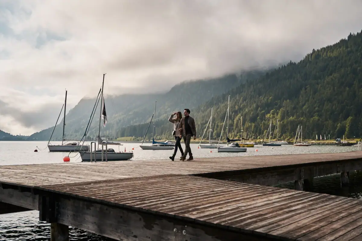 Shore of Lake Achensee A couple walks on a jetty on Lake Achensee with boats in the background.
