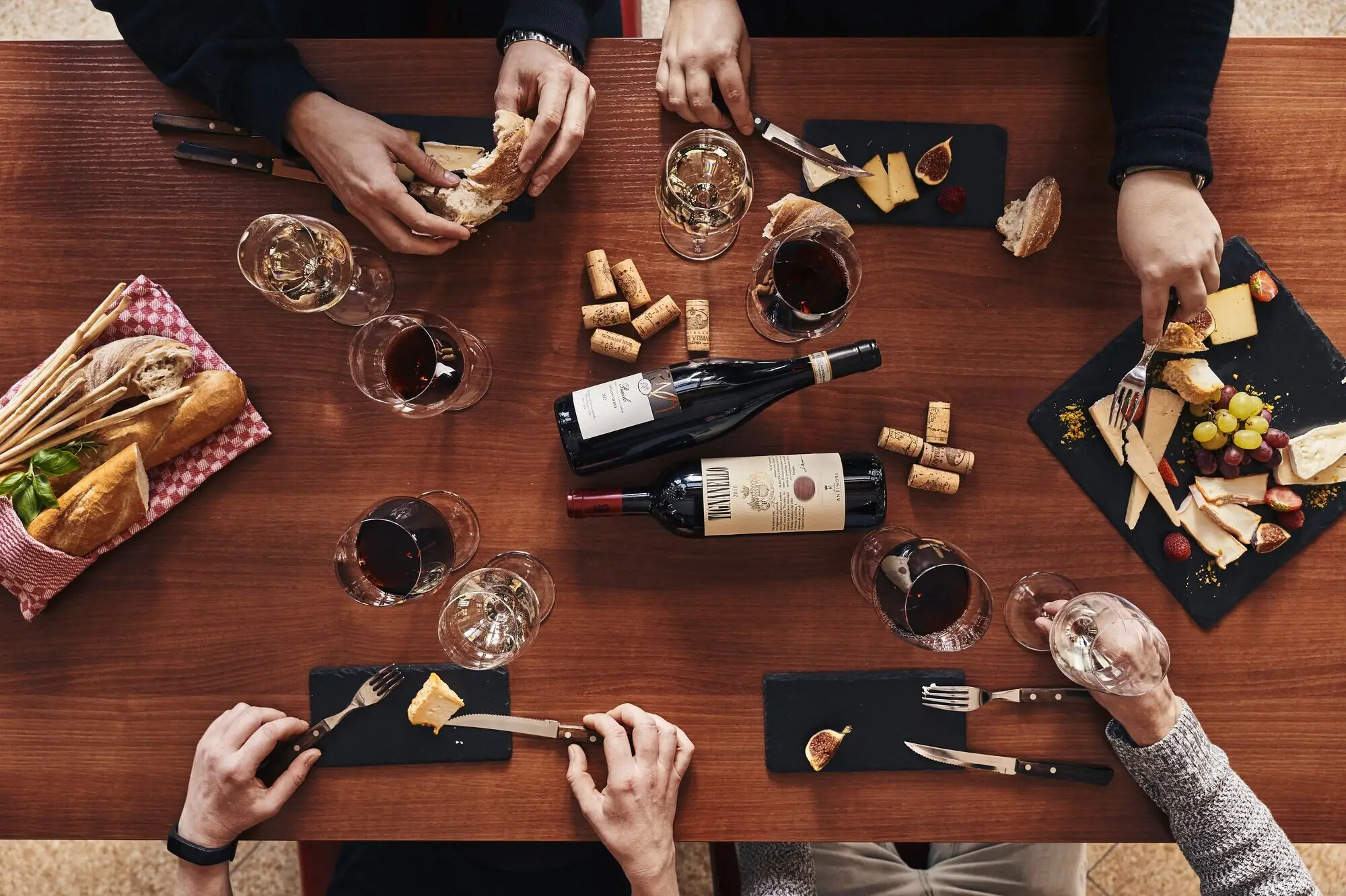 A group of people eat at a table with wine glasses and food.