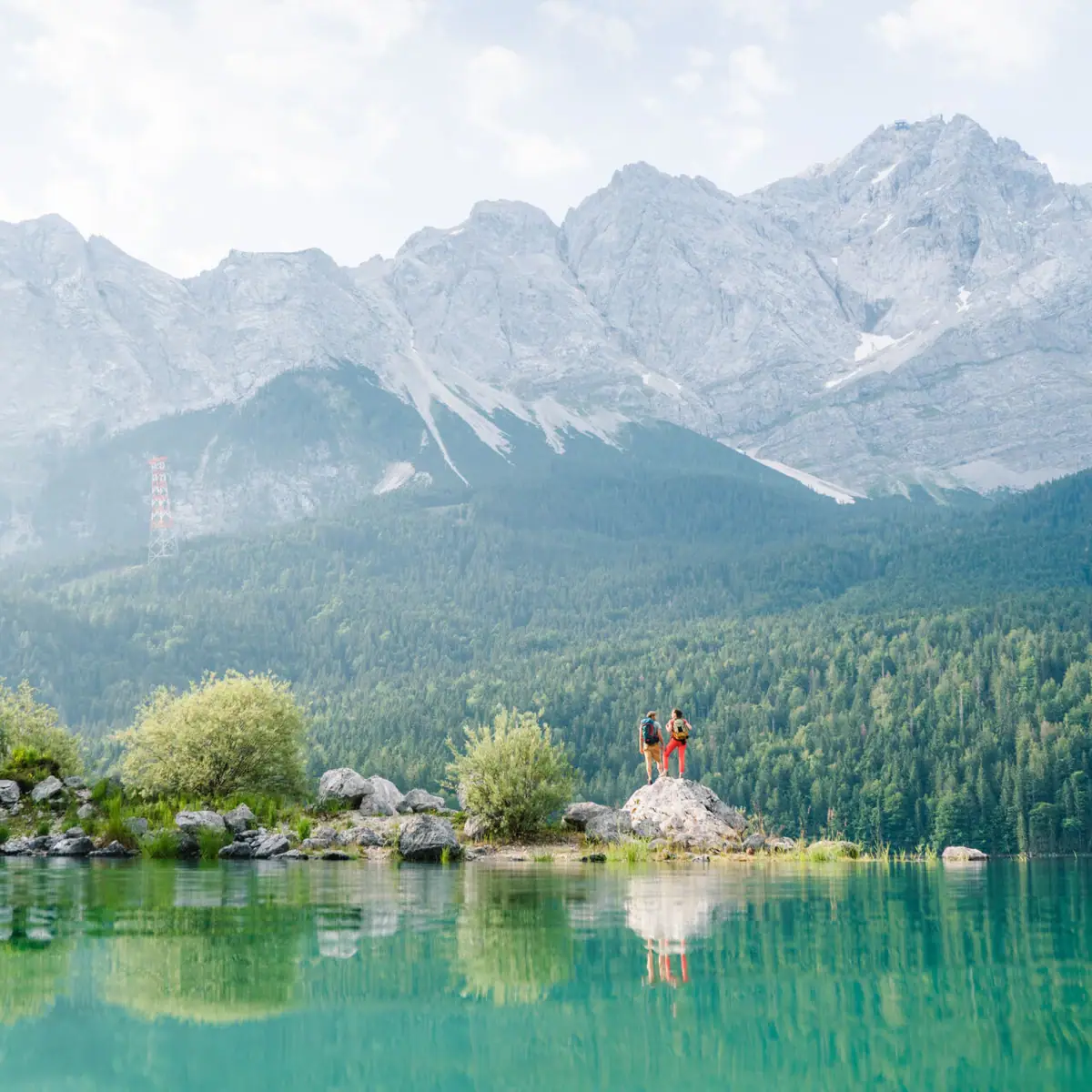 People standing on a rock in front of a lake.