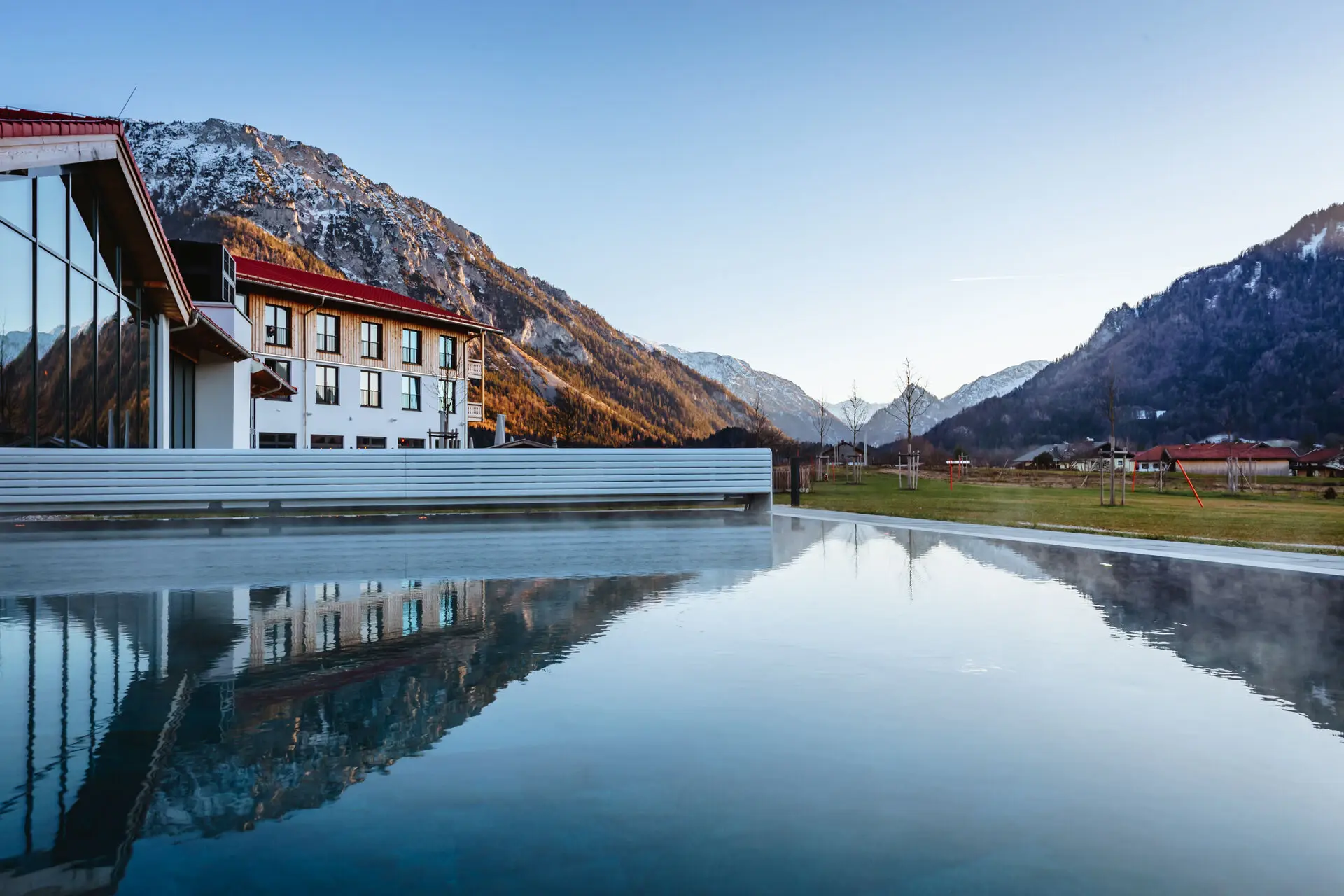 Outdoor pool at aja Ruhpolding A pool with a building in the background.