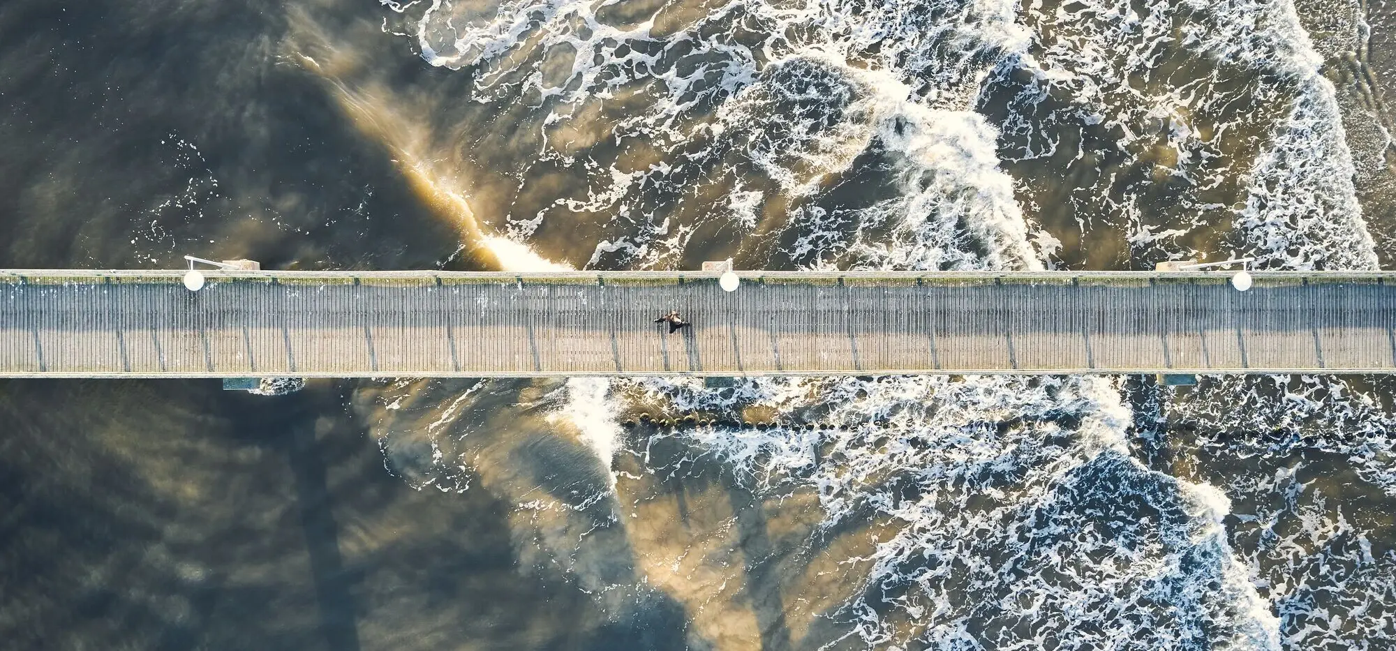 A pier with a person on it from above.