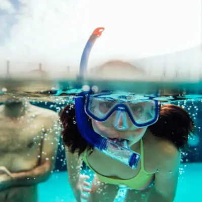 Swimming courses A girl in a swimming costume and swimming goggles under water.