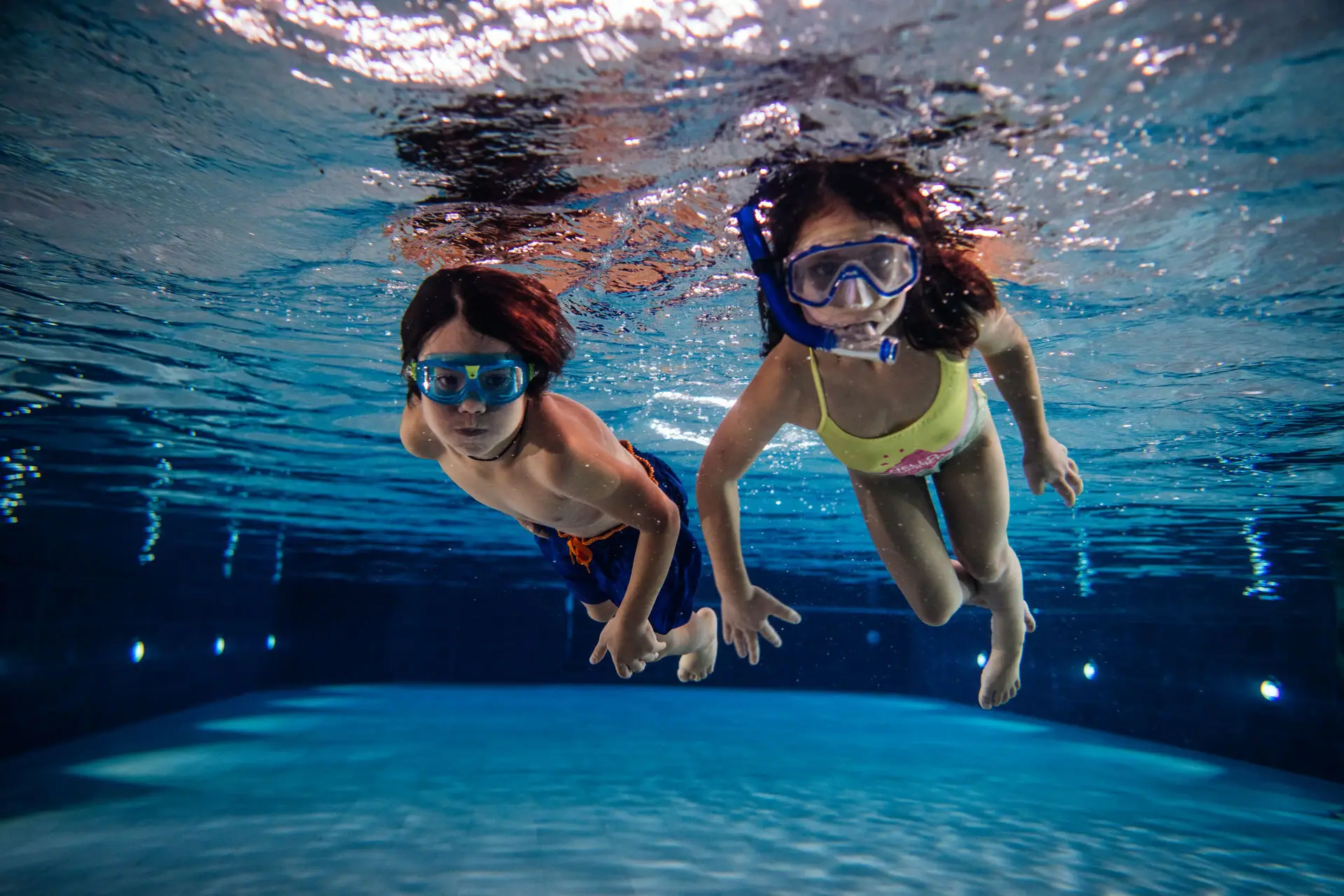 Children diving in the pool Several people are swimming underwater in the pool.
