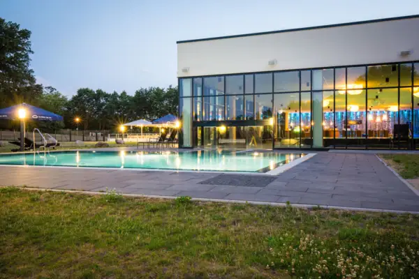 A building with a swimming pool and lawn.