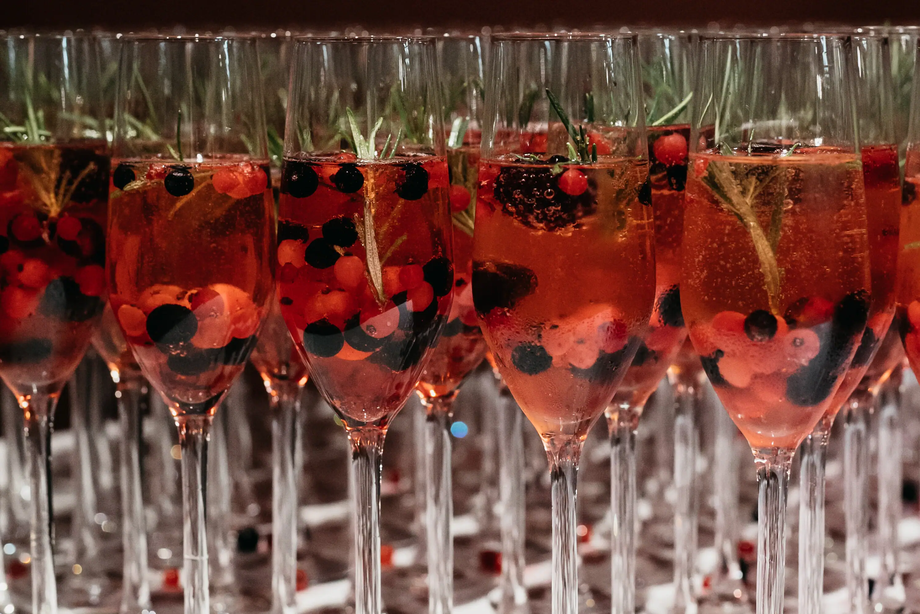 A group of glasses with red liquid and berries.