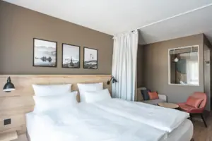 A bed with white sheets and pillows in a room with pictures on the wall.