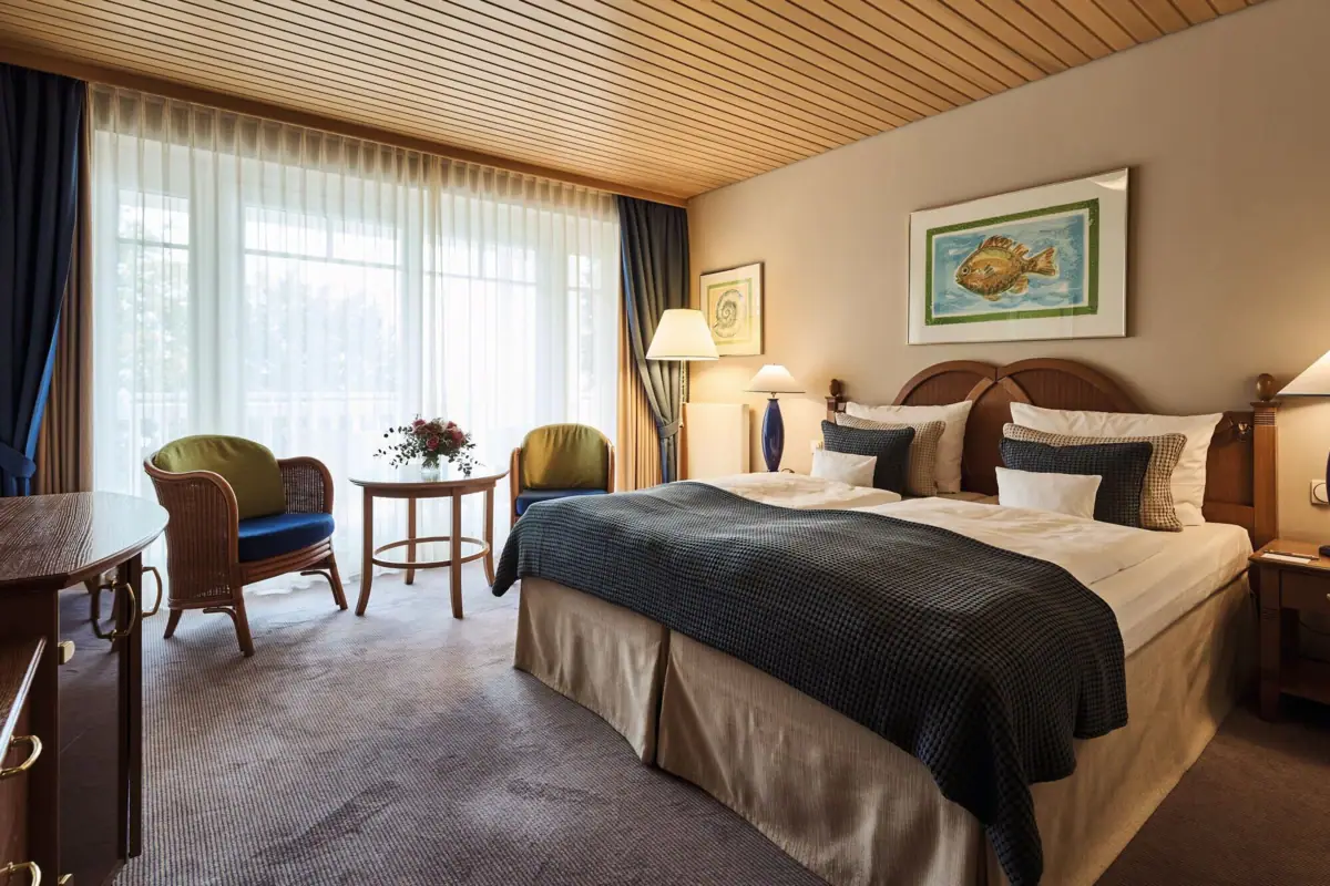 A bedroom with a bed and chairs.