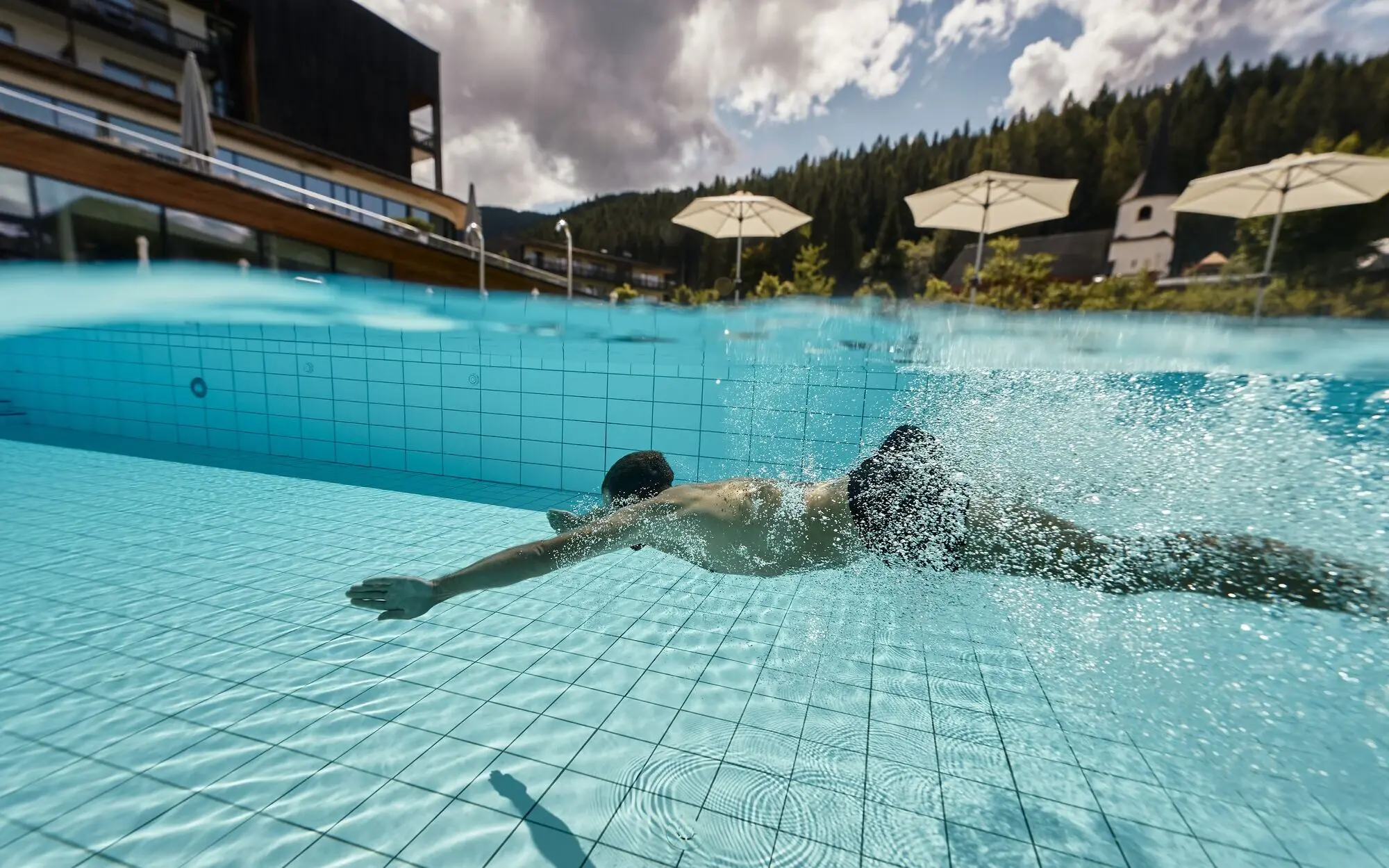 A man dives in the outdoor pool of the aja Werfenweng.