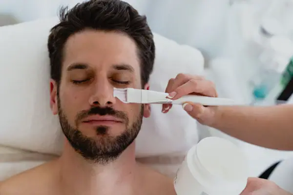 Man receiving a facial mask treatment indoors.