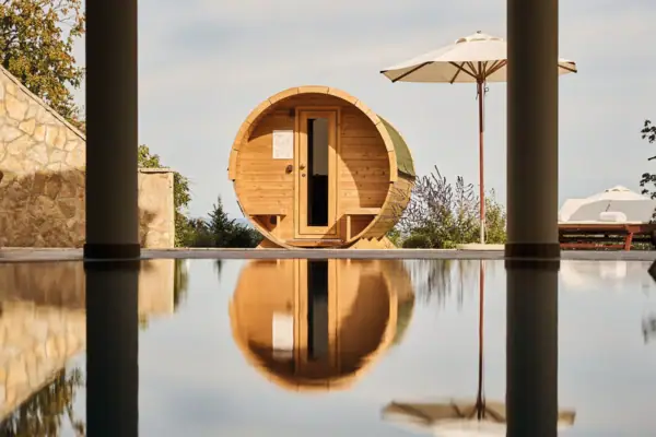 Fasssauna Eine holzfassförmige Sauna neben einem Pool.