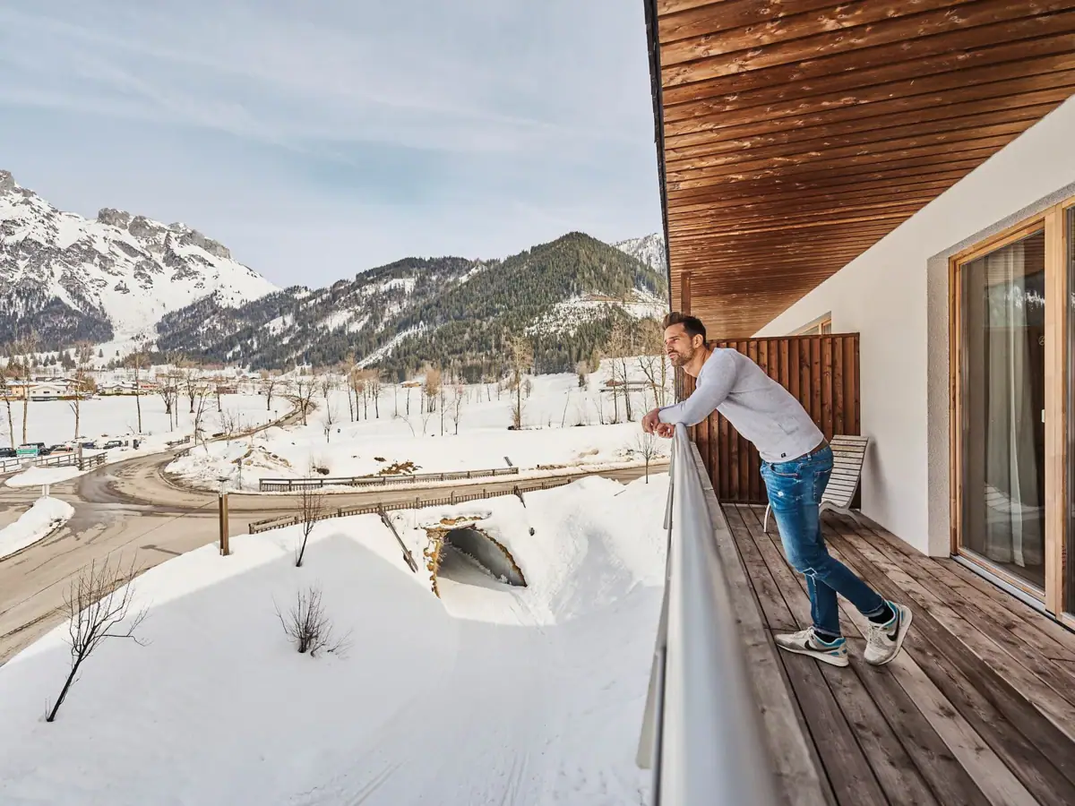 Balcony Werfenweng A man stands on a snow-covered balcony.