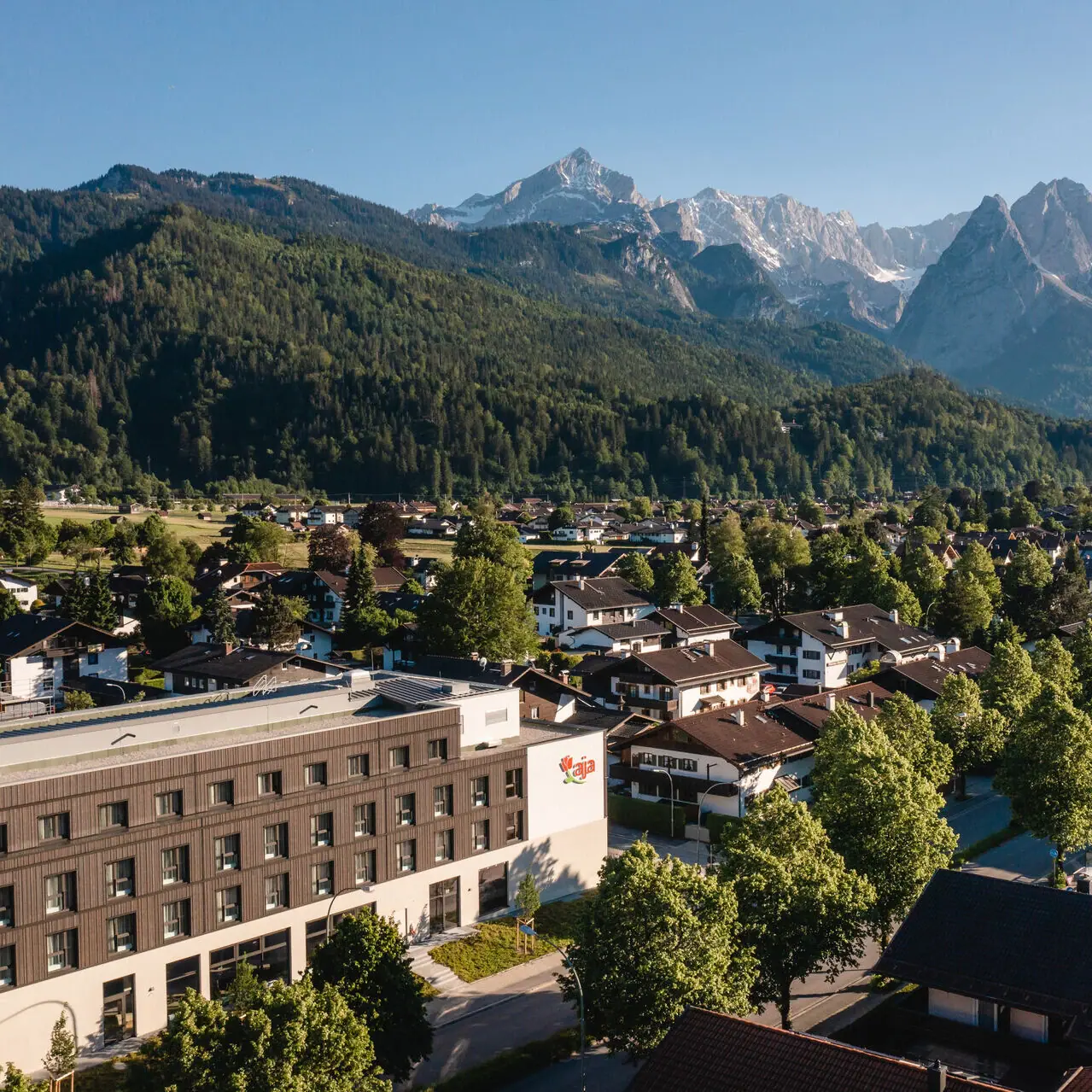 The aja Garmisch-Partenkirchen with trees and mountains in the background.