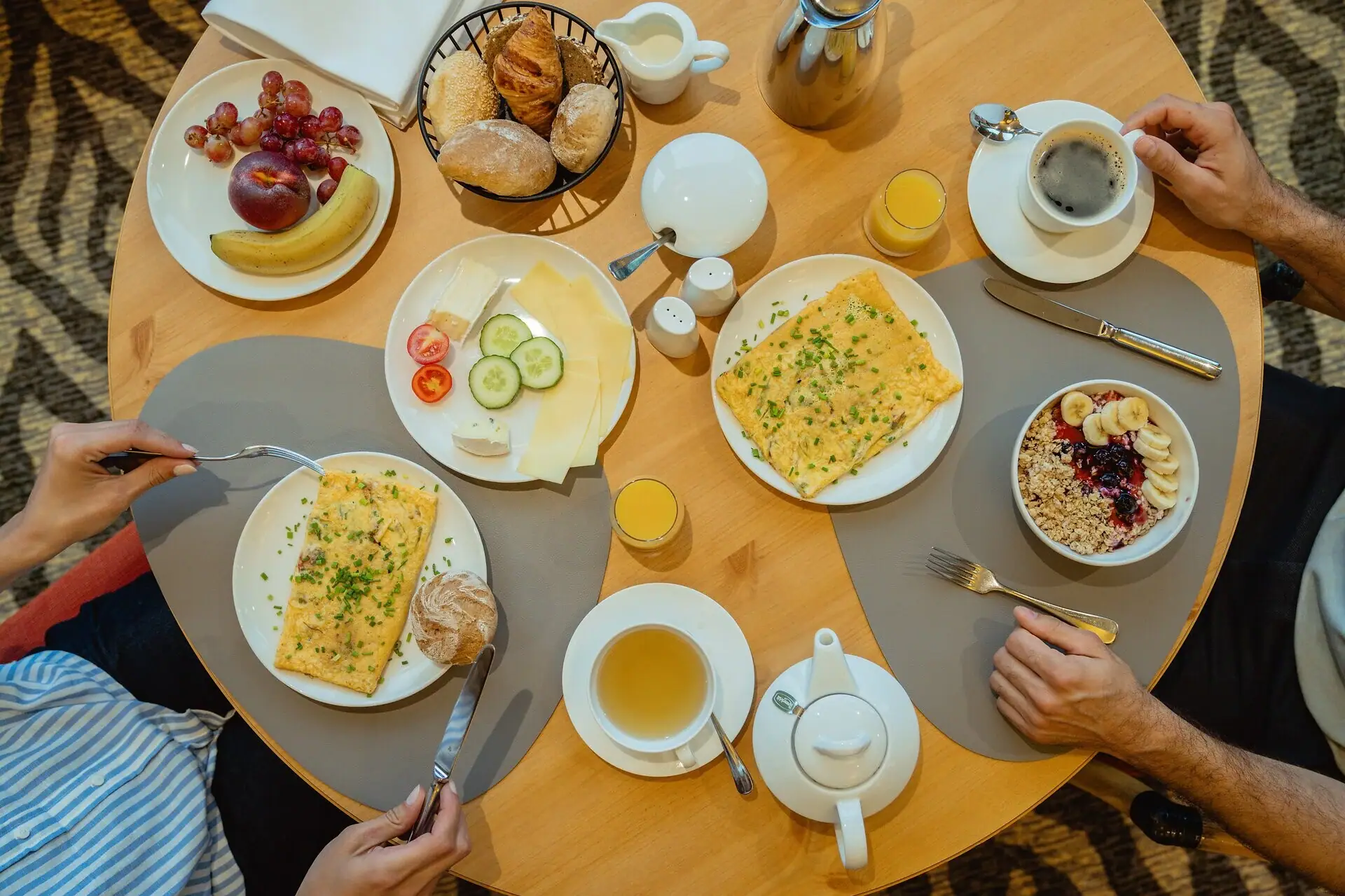 Breakfast table A person eats at a table with various dishes on plates.