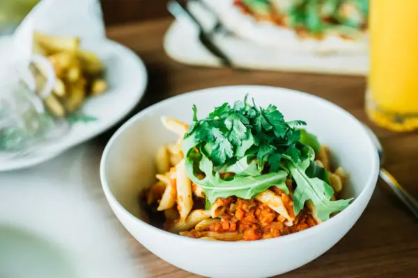 Lentil bolognese A bowl of pasta with sauce and green ingredients.