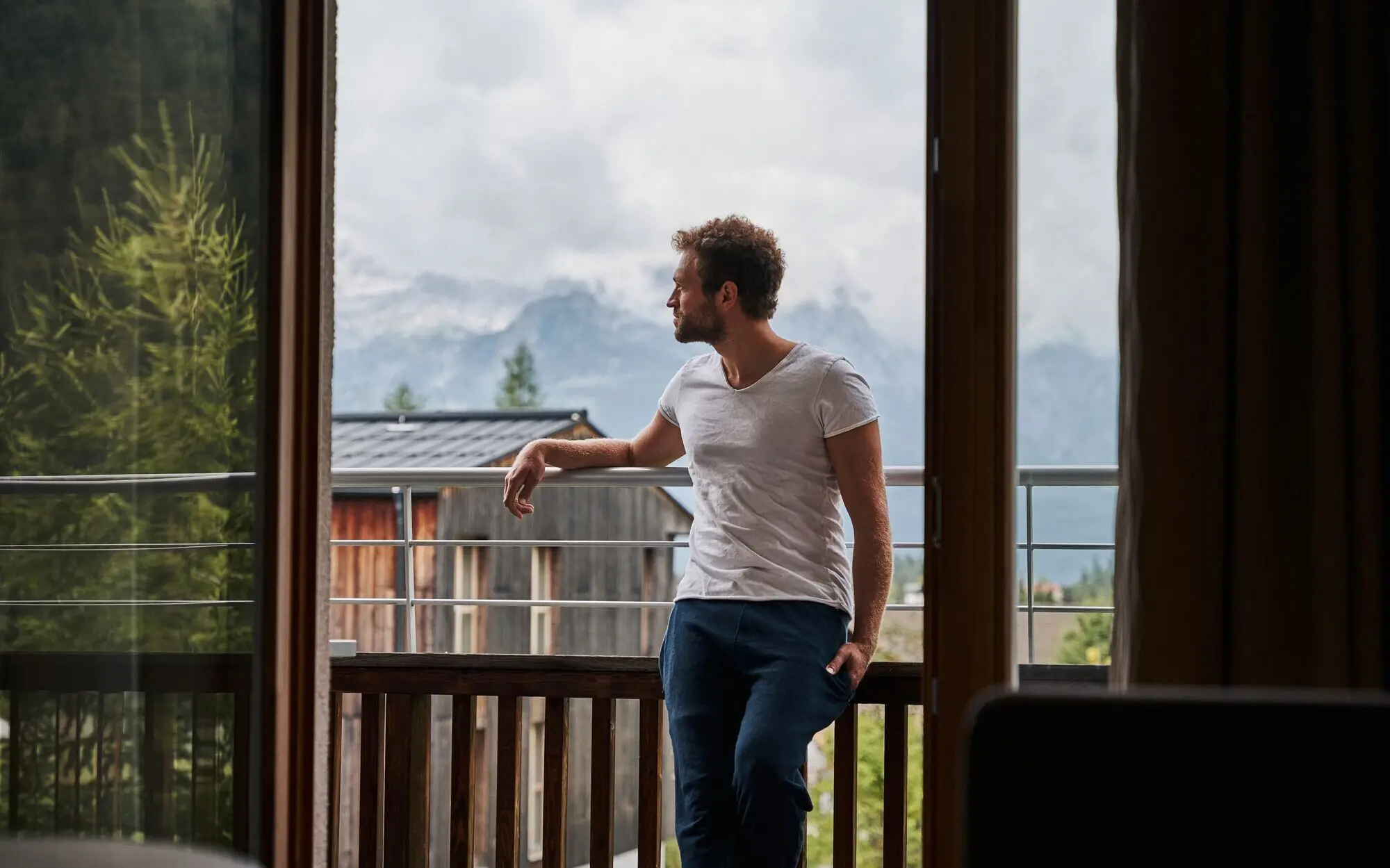 Man leaning against a railing and looking out through a window.