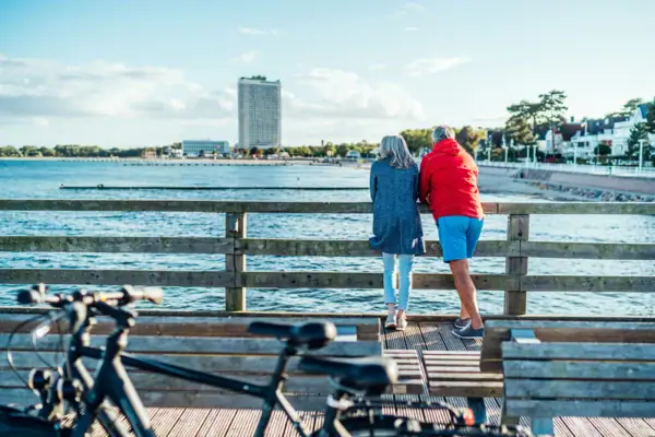 Couple by the sea A man and a woman stand on a wooden bridge and look out over the water.