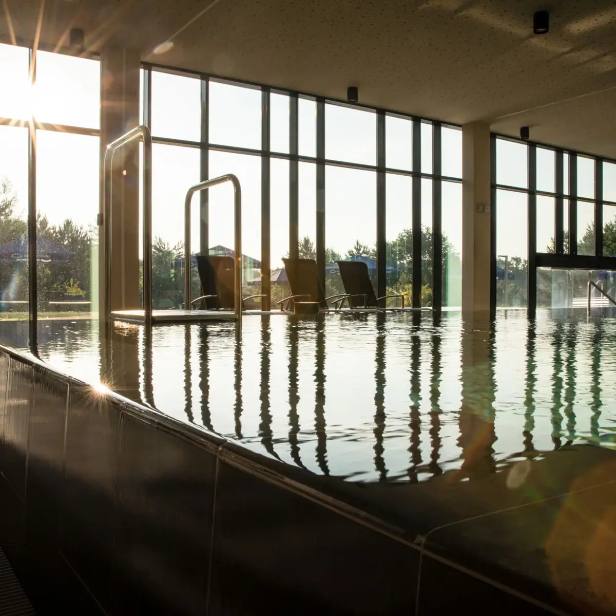 Contact & opening hours A pool with a large window and water reflections.