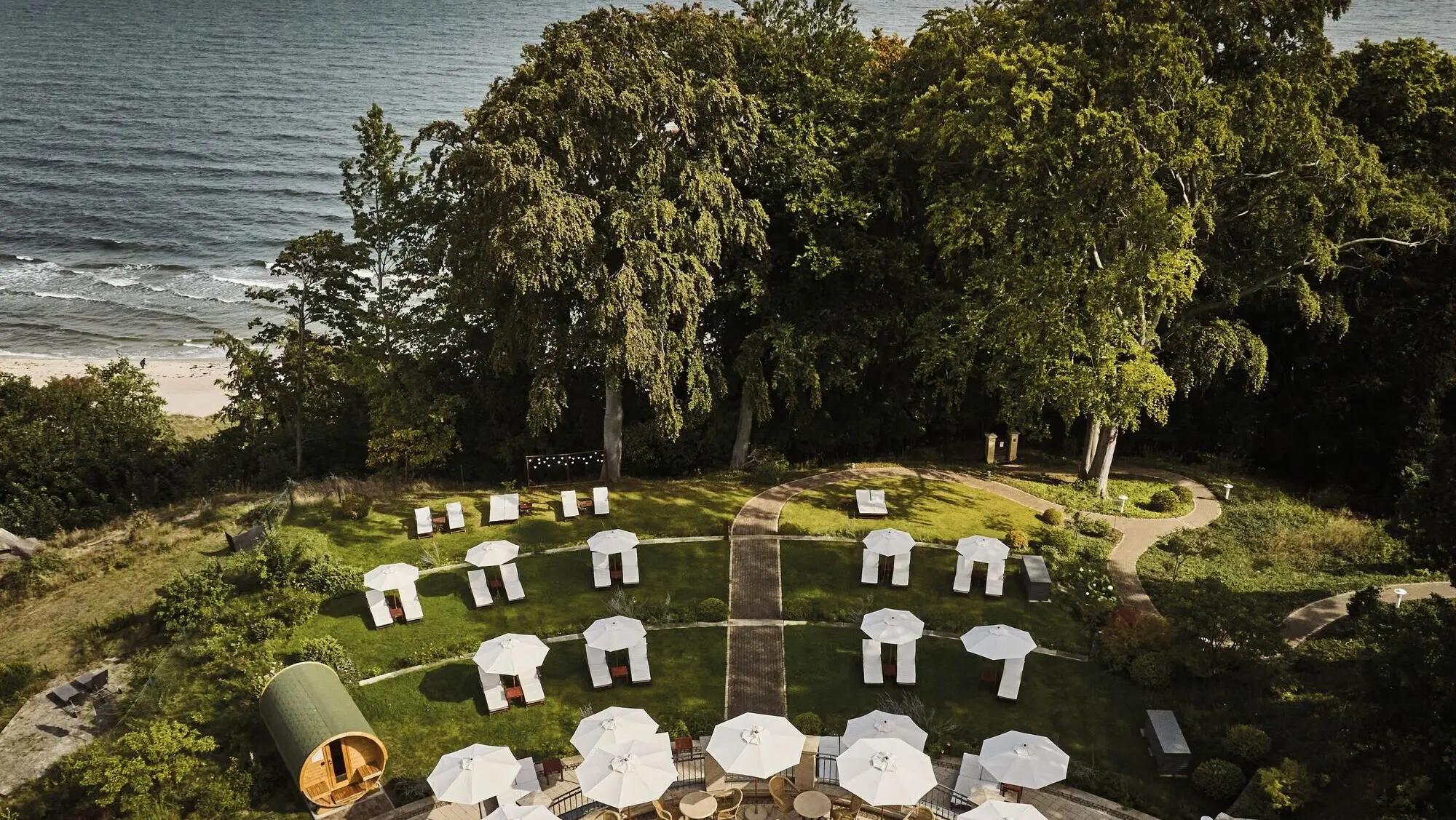 White tents on a meadow with trees and a body of water in the background.