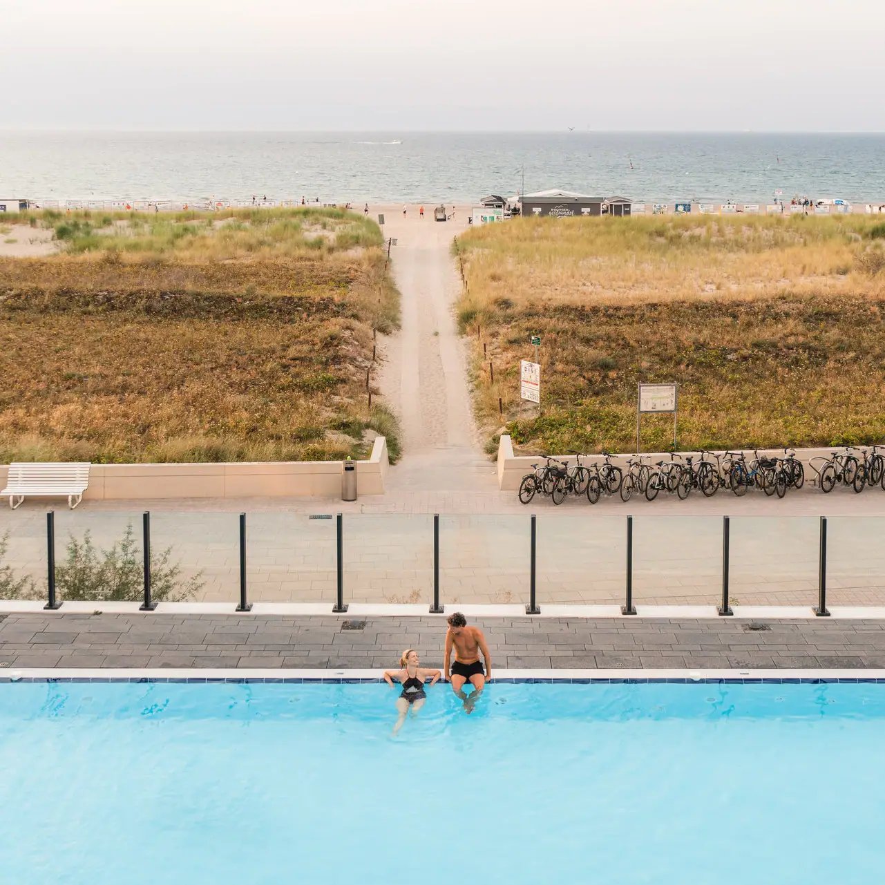 Wellness at the aja Warnemünde A man and a woman in the pool with a view of the beach.