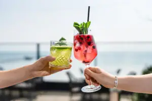 Ein Paar Hände hält Cocktails mit Erdbeergarnitur.