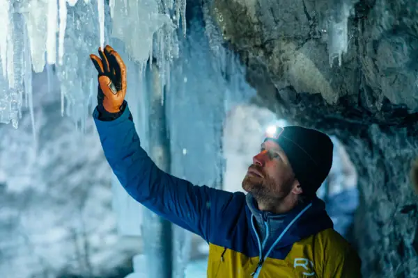 A man with a head torch in the Partnachklamm gorge looks at an icicle.