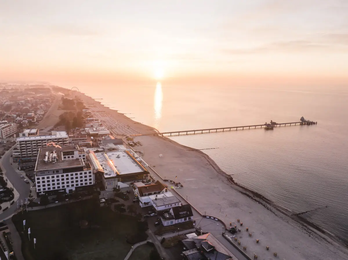 A beach with a pier and buildings at sunset.