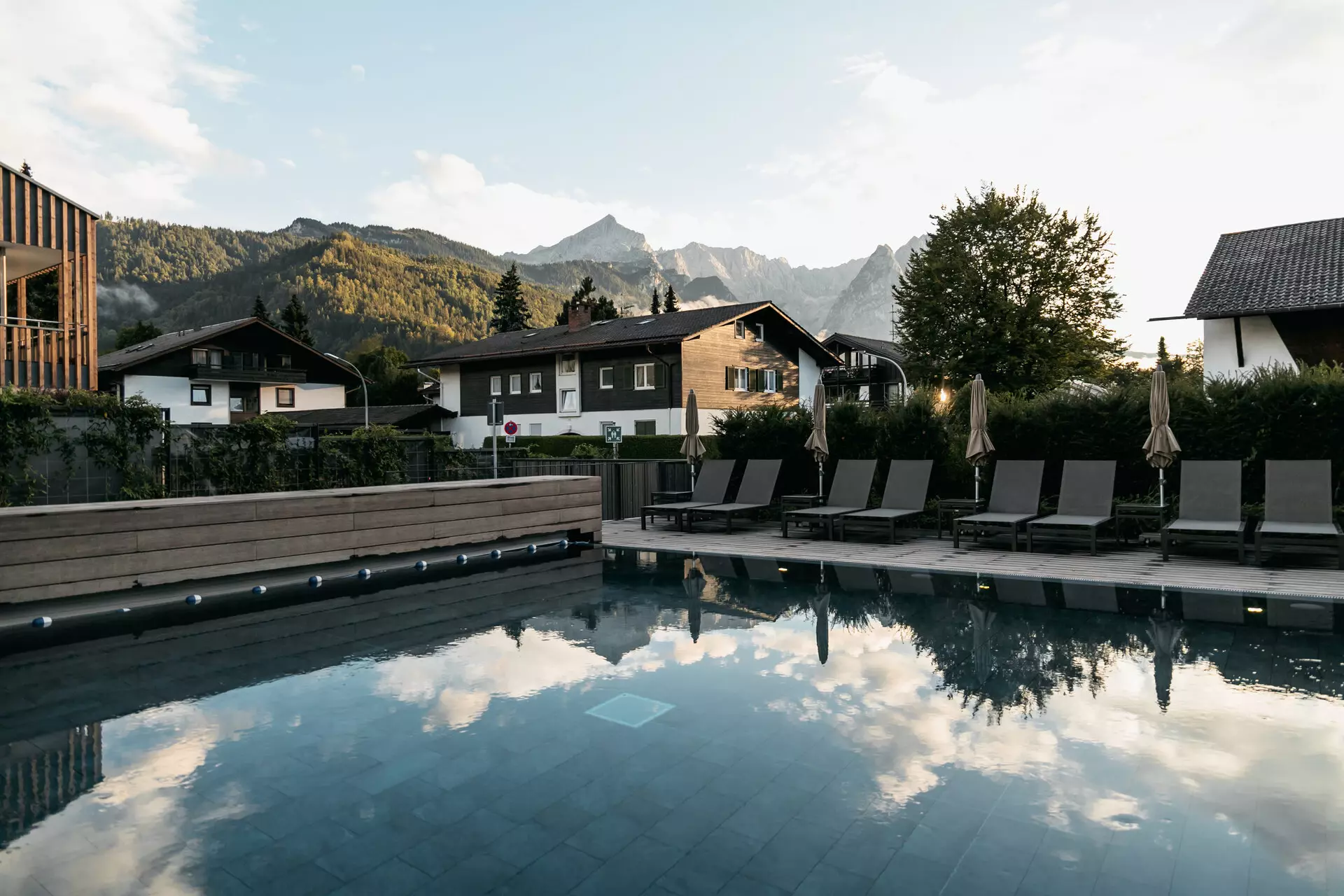 Outdoor pool with chairs and a building in the background.