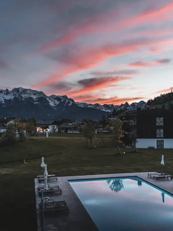 A pool in a grassy area with mountains in the background.